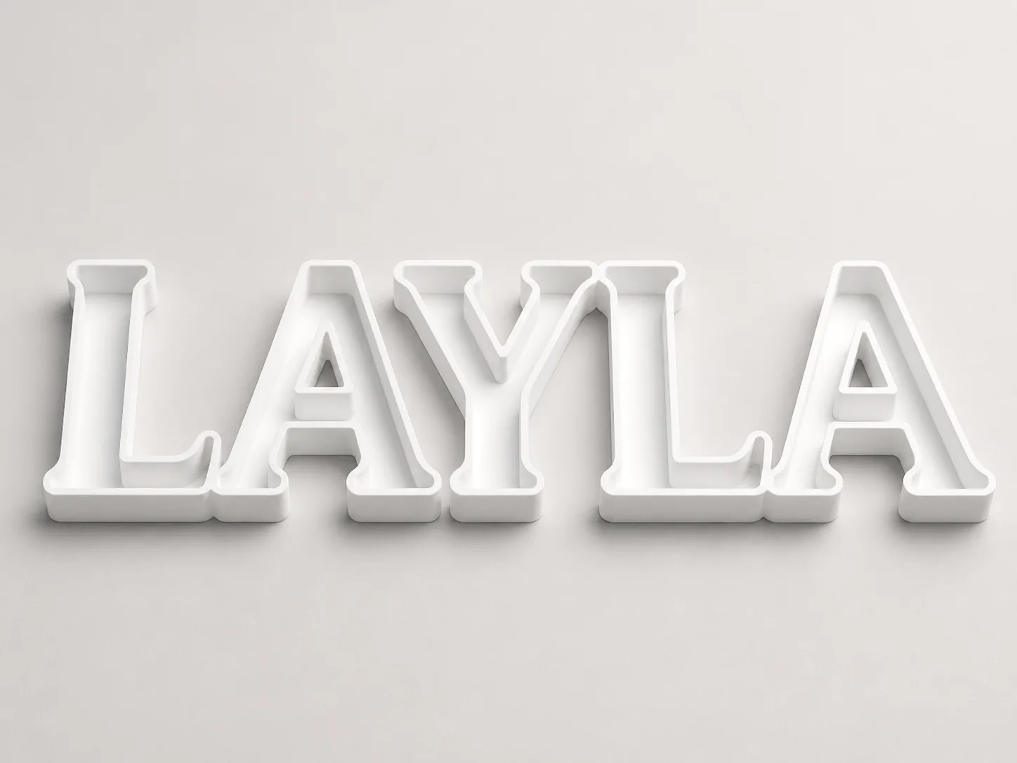 Five separate white 3D-printed letters spelling LAYLA in chunky slab-serif capitals, each with a recessed face inside a raised outline wall, lit softly against a pale grey background